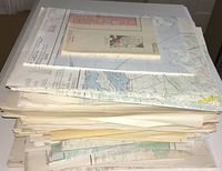Pile of folded and flat vintage maps stacked on shelf