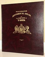 Front cover of the Illustrated Historical Atlas of the County of York with gold embossed title and crest on a maroon background.