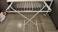 White metal Ikea clothes drying rack with grid surface, foldable, shown fully set up.