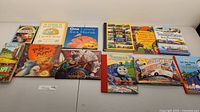 Photo showing a collection of 13 children's books laid out side by side, covers visible.