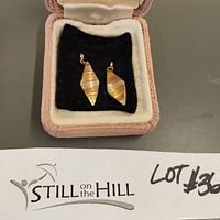 Vintage delicate gold drop earrings with diamond shape and horizontal stripe textures in different gold tones, displayed in a pink velvet jewelry box.