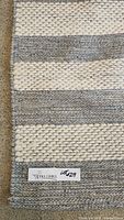 Close-up photo showing the woven wool texture and striped pattern in cream and grey.