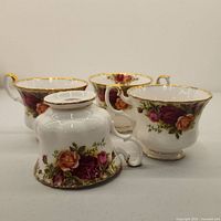 Three bone china teacups showing floral rose pattern and gold trim