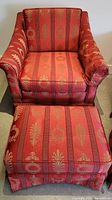 Close front view of one red and gold striped vintage armchair with matching ottoman.
