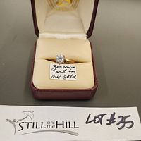 Front view of vintage 10k gold ring with a cubic zirconia stone in a maroon ring box with a label 'Zirconia set in 10k gold'