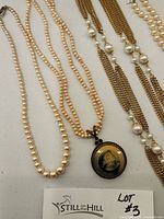 Photo showing three cultured pearl necklaces, one Extasia cameo necklace pendant and partial view of jewelry box.