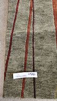 Top section of the area rug showing forest green base with red and maroon stripes.