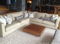 Wide shot of cream-colored L-shaped sectional sofa in living room with decorative throw pillows and wooden coffee table