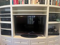 Samsung LCD TV installed in white built-in cabinetry, flanked by audio components and turntable