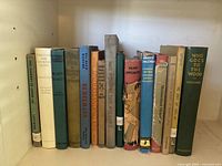 Shelf of vintage hardcover and paperback children's books, including Moomin books and classic literature.