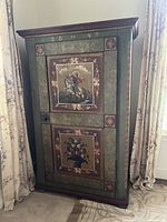 Full front view of antique hand-painted wooden armoire showing top and lower painted panels with St. George slaying the dragon and a vase of flowers.