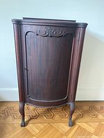Front view of the antique wood cabinet showing carved door and legs.