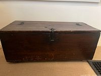 Front view of an antique wooden chest showing latch and wood surface.