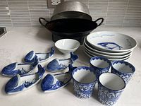 All items arranged on kitchen counter showing woks, ceramic plates, bowls, and whale-shaped plates.