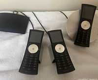 Three Bang & Olufsen BeoCom 5 speaker phone handsets displayed on white surface with bases and charging stands.