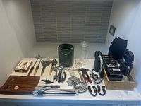 Overview of entire barware set laid out on counter including box, loose tools, bottle stoppers, ice bucket, and accessories.