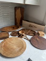 Overview of various wooden kitchenware including plates, bowls, boards, and box on countertop.
