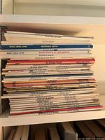 Spine view showing a tall stack of paperback comic books, primarily Asterix series with various titles visible including 'Asterix and the Golden Sickle,' 'Asterix and the Chieftain's Shield,' and others.