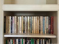 First shelf of diverse hardcover and paperback books displaying titles predominantly from classic literature, mystery, and drama genres.