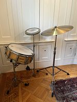 Photo of the drum set showing Pearl snare drum on stand, Remo practice pad on separate stand, and Zildjian cymbal on stand.