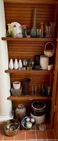 Full shelf view of multiple vases and decor items including glass, ceramic and metal pieces in various shapes, colors and sizes