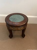 Front angle showing carved wood apron with cloud motifs and the inset marble top on the footstool