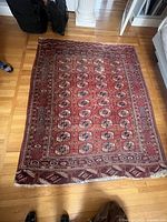 Full view of the medium-sized red wool Persian rug laid flat on hardwood floor showing overall geometric pattern and border design.