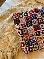 Photo showing both crocheted blankets, beige chevron pattern and multicolor granny square.