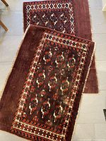 Both Persian wool rugs laid out showing geometric patterns and visible wear, discoloration.