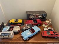 Overview of diecast model cars in various colors and boxes arranged on wooden table