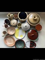 Overhead view of all pottery items grouped together showing variety of sizes and shapes, including lidded dishes, pitchers, mugs, bowls, and plates in natural rustic colors.