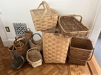 Photo showing 10 vintage basketry pieces including hamper, large baskets, and smaller baskets arranged on wooden floor
