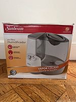 Front of the unopened Sunbeam filter-free console humidifier box with product image and basic feature highlights in Spanish.