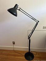 Full view of lamp showing adjustable swing arm and round base