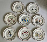 All 8 vintage song lyric ceramic dessert plates arranged on a flat surface, showing colorful illustrations and lyrics on each plate.