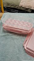 Photo showing one pink plastic egg container with transparent locking lid and egg slots inside.