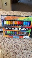 Front of box showing 24 tubes of acrylic paints in 24 different colors arranged in two rows