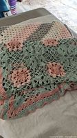 Photo showing the floral crochet squares with pink flowers and green lattice background layered over the striped crochet blanket sections.