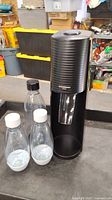 SodaStream Terra black sparkling water maker with three bottles on table in workshop environment