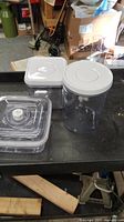 Three plastic containers with matching white vacuum lids on dark surface