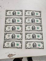 Front side of 10 sequential $2 bills showing Thomas Jefferson portrait and serial numbers.