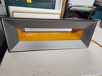 Front view of the Airocide air filter with yellow central panel and perforated metal grille.