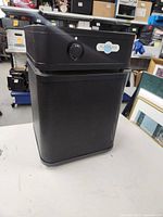 Front and side view of black Austin Air air purifier showing the metal grille and overall compact design.