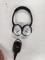 Over-ear Bose headphones showing damage and wear, black with silver accents with the Bose logo on the ear cups