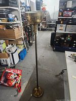 Full view of the brass standing floor lamp showing its round base, tall slender pole, and bowl-shaped shade in an indoor setting.