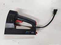 Side view of black Craftsman electric stapler/nailer with attached power cord and red trigger.