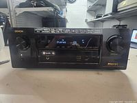 Front view of Denon AVR-X2300W AV receiver showing display, control knobs, and front ports.