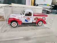Side view of diecast Ford pickup truck with Pepsi-Cola graphics inside clear plastic packaging.