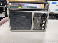 Front view of General Electric AM/FM receiver radio showing speaker grill, tuning dial, and control buttons.