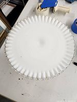 Top view of the white glass cake stand showing the ruffled edge design with clear glass tips.